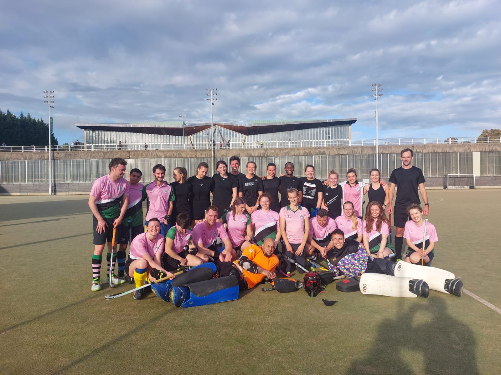 Group of people standing on a hockey pitch smiling